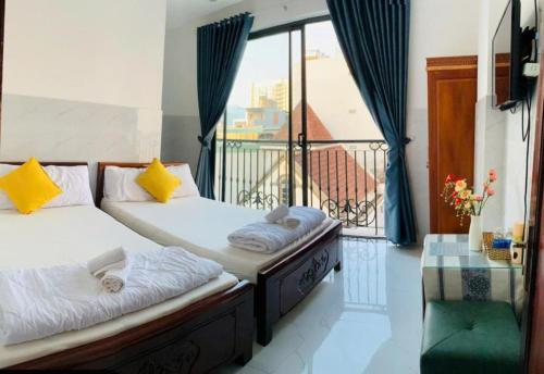 two beds in a room with a balcony at Tây Nguyên hotel Đà Nẵng in Danang