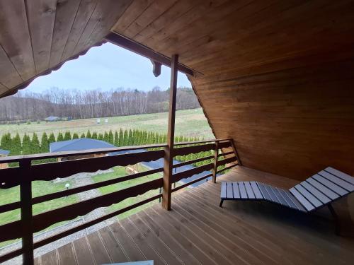 a wooden porch with a bench and a view of a field at Dom u Julii Bieszczady in Ustrzyki Dolne