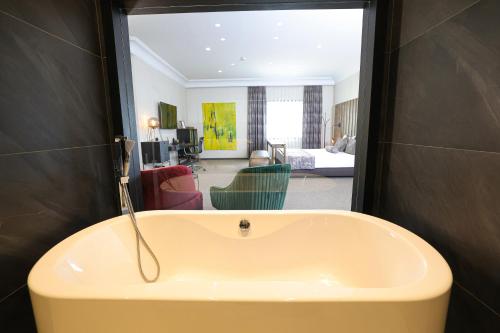 a bathroom with a tub and a living room at Hotel Rubis in Ferizaj