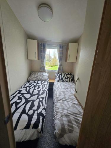 two beds in a small room with a window at Lapwing 26 in Scratby