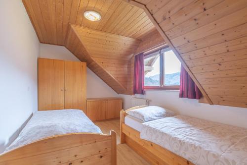 two beds in a room with wooden ceilings at Tourist farm Mulej in Bled