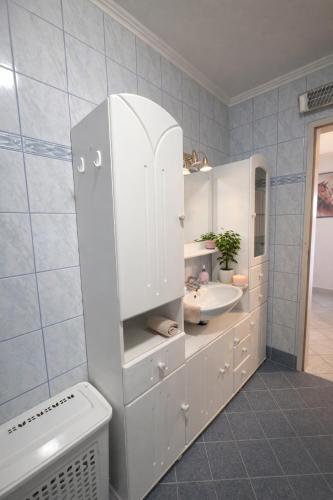 a white bathroom with a sink and a mirror at GUESTHOUSE Kastel Novi 2 More Space in Kaštela