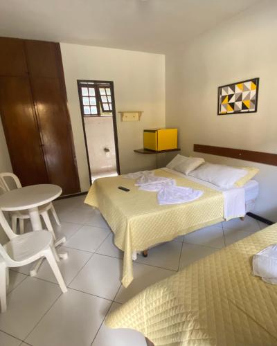 a bedroom with two beds and a table and chair at Pousada Recanto do Alto de Teresópolis in Teresópolis