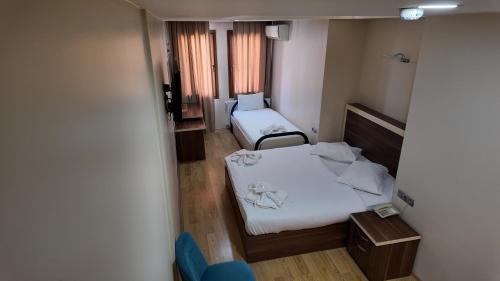 a small room with two beds and a chair at Merkez Otel in İzmir