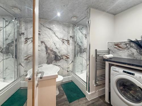 a bathroom with a shower and a washing machine at Bletchley Retreat in Bletchley