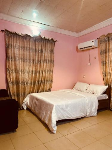 a bedroom with a white bed and pink walls at Executive 2BR at Redemption Camp in Loburo