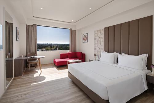 a bedroom with a large white bed and a red chair at Treat Resort Rajkot in Rajkot