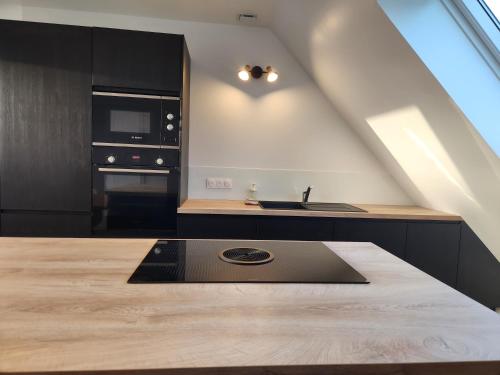 a kitchen with black cabinets and a wooden table at O'Phare Ouest in Plouguerneau