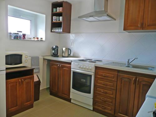 a kitchen with wooden cabinets and a white stove top oven at Prízemný apartmán Anika s veľkým parkovaním in Nitra