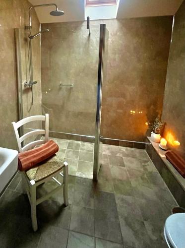 a bathroom with a shower and a chair and a sink at Cosy Cottage for Two in the Peak District with Parking in Onecote