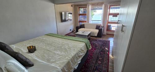 a bedroom with a bed and a chair and a window at Apex Ocean and Mountainview in Gordonʼs Bay