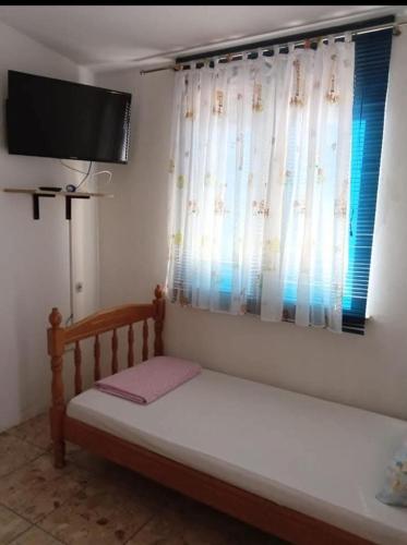 a bed in a room with a television and a window at Apartmani Marija Rtina in Rtina