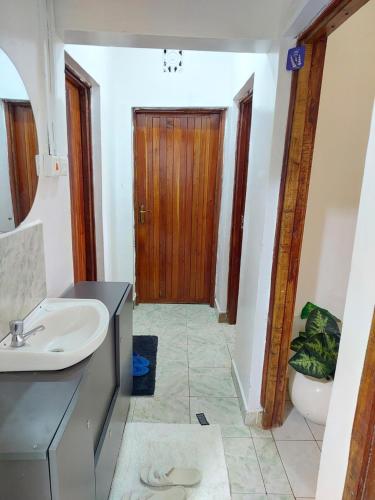 a bathroom with a sink and a wooden door at JJHomes in Eldoret