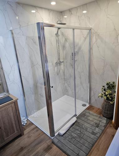 a shower with a glass door in a bathroom at Letterfinlay Lodge House in Letterfinlay