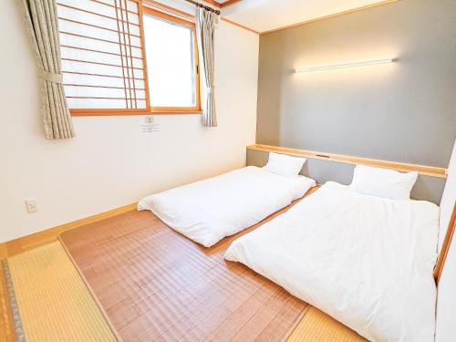 two beds in a room with a window at House Villa Kagura in Asahikawa