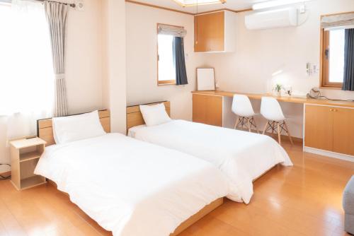two beds in a white room with a kitchen at House Villa Kagura in Asahikawa