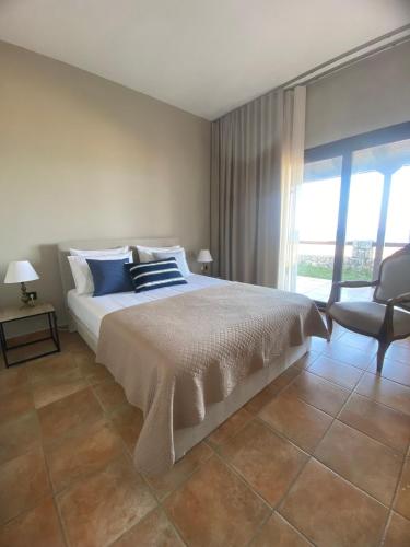 a bedroom with a bed and a chair and a window at Villa Agali in Agia Anna
