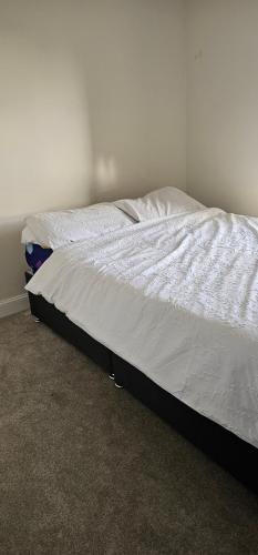 an unmade bed with white sheets in a bedroom at Private room in a 2-bedroom house in Dinnington