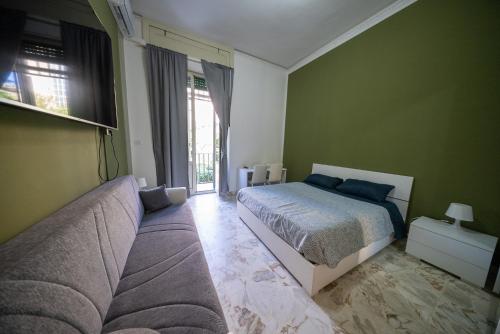 a bedroom with a bed and a couch and a window at Mi casa tu casa - Guest House in Catania