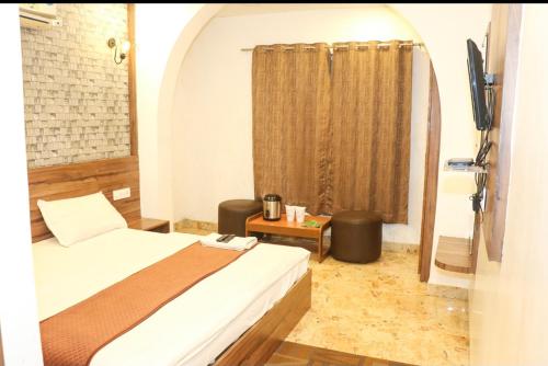 a bedroom with a bed and a window with a curtain at Hotel Meghdoot in Pachmarhī
