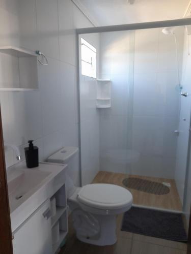 a white bathroom with a toilet and a shower at Studio Duplex Praia do Porto in Imbituba