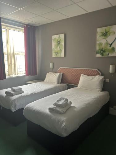 two beds in a hotel room with towels on them at The Grand Hotel in Port Talbot