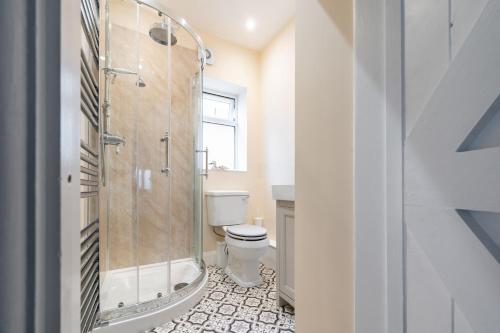 a bathroom with a shower and a toilet and a window at Petts Cottage in Burnham Market