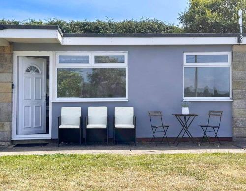 a group of chairs sitting outside of a house at Seaside Serenity at Ocean Days in Brading