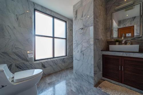 a bathroom with a toilet and a sink and a window at Malee Beach C8 in Phra Ae beach