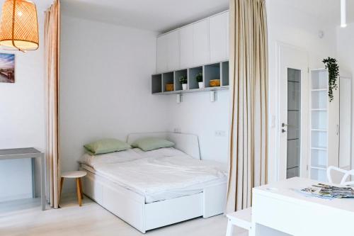 a small white bedroom with a bed and a desk at Azure Bay Residence in Balatonfenyves