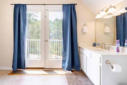 a bathroom with a large window with blue curtains at L'Hermione in Gloucester
