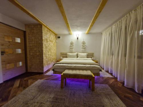 a bedroom with a king sized bed and a bench at Cabana din Padurea Valeni in Vălenii de Munte