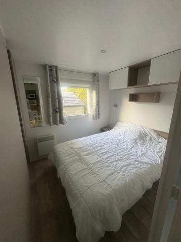 a bedroom with a large white bed with a window at mobilhome 5 personnes in Saint-Arnoult