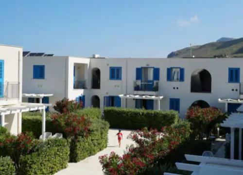 a person walking down a sidewalk in front of a building at Macari Residence Central Apartment in Macari