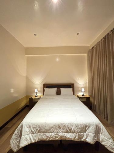 a bedroom with a large bed with two lamps on tables at Terrazas 3400 Lodge in Oxapampa