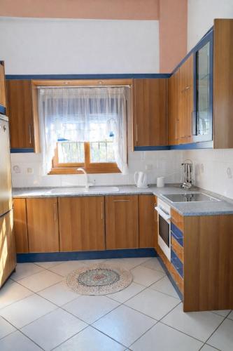 a kitchen with wooden cabinets and a window at Private Villa Sea View BBQ in Epanomi