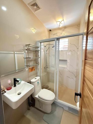a bathroom with a toilet and a sink and a shower at Modern Loft-Balcony-FullAC open space in Calumpit