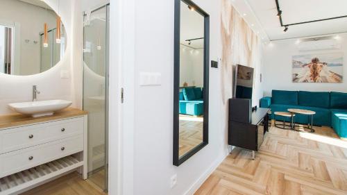 a bathroom with a sink and a blue couch at Apartament 19A - Villa Neptun in Gdańsk
