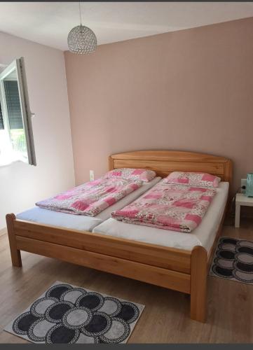 a bedroom with a bed with pink and white sheets at Apartman Sunce in Jerkovići