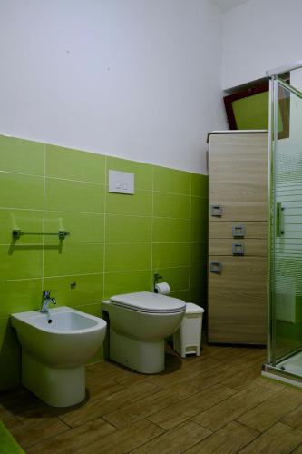 a green bathroom with a toilet and a sink at Antonella's house in Casteldaccia