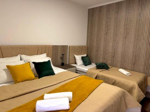 a hotel room with two beds with yellow and green pillows at Apartmani Vučinić in Cetinje