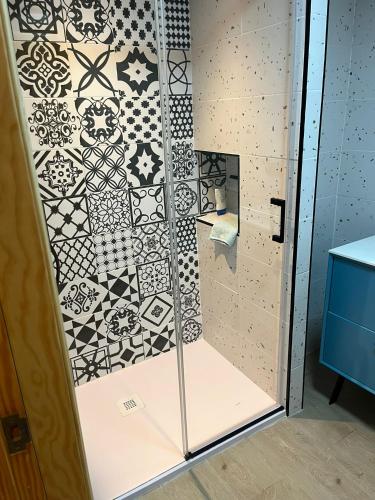 a shower with black and white tiles on the wall at La casa de Inocen in Cilleruelo