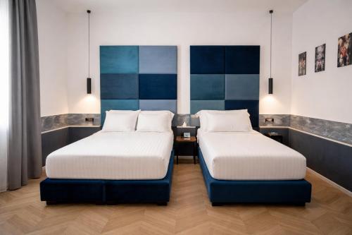 two beds in a room with blue and white at Hotiday Napoli Maradona in Naples