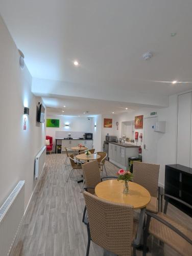 a living room with tables and chairs and a kitchen at The Hive Great Yarmouth in Great Yarmouth