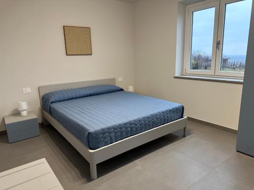 a white bedroom with a bed and a window at Casa Piutin, appartamento Bucaneve in Bagnolo Piemonte
