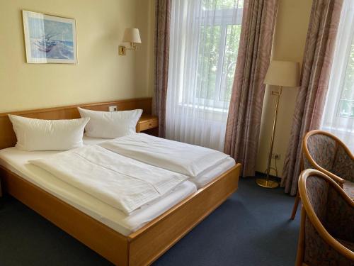 a bedroom with a bed with white sheets and a window at Hotel Drei Rosen in Borna