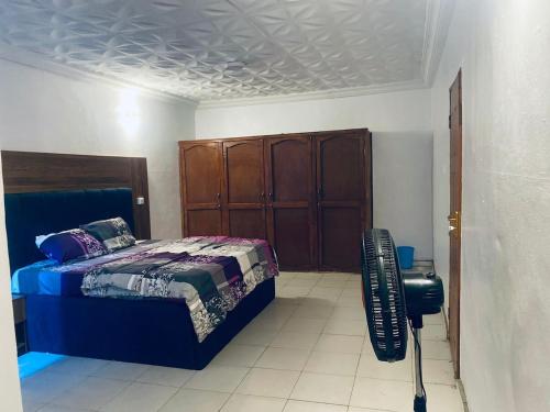 a bedroom with a bed and a wooden cabinet at KFP Serene and Modern 2BR Flat , IBD in Ibadan