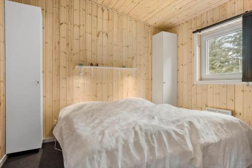 a bedroom with a bed in a wooden wall at LF10202-Thyholm-Markvejen-2 in Thyholm