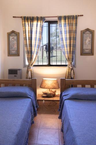 a bedroom with two beds and a window at La Cuadra - Puesto de Campo Argentino in Lobos