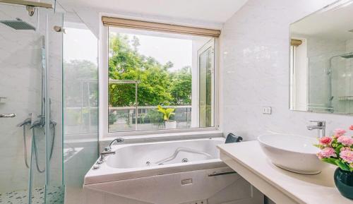 a bathroom with a tub and a sink and a window at FLC Sam Son Grand Pool Villa NT48 7BR Near Beach in Sầm Sơn